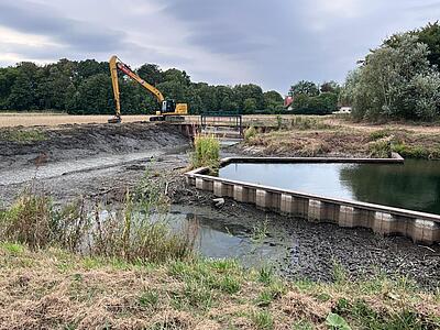 Ein Bagger steht am Ufer.