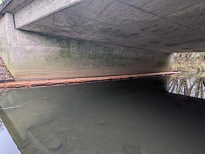 Berme im Wasser entlang der Wand eines Brückenpfeilers