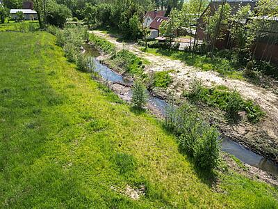 Die Hunte fließt durch Wiese. Im Flussbett sind die Kiesbänke zu erkennen.