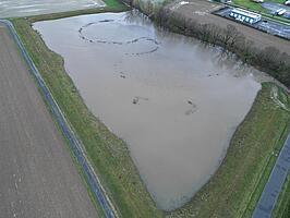 Luftaufnahme eines überfluteten gebiets zwischen Deichen, umgeben von Feldern und Straßen