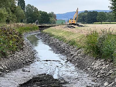 Ein Bagger steht am Ufer.